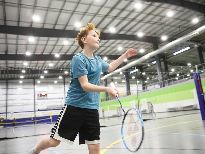 Schüler in der Sporthalle beim Badminton spielen